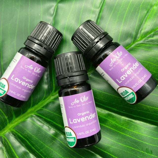 Three lavender essential oil bottles with purple labels against a variegated-leaf background.